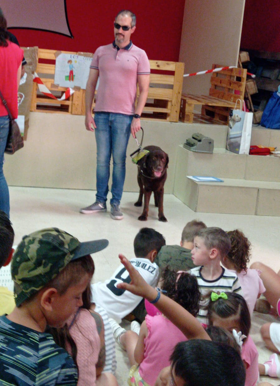 David Enrique junto a su perra-guía Valeri enseñando movilidad a los niños