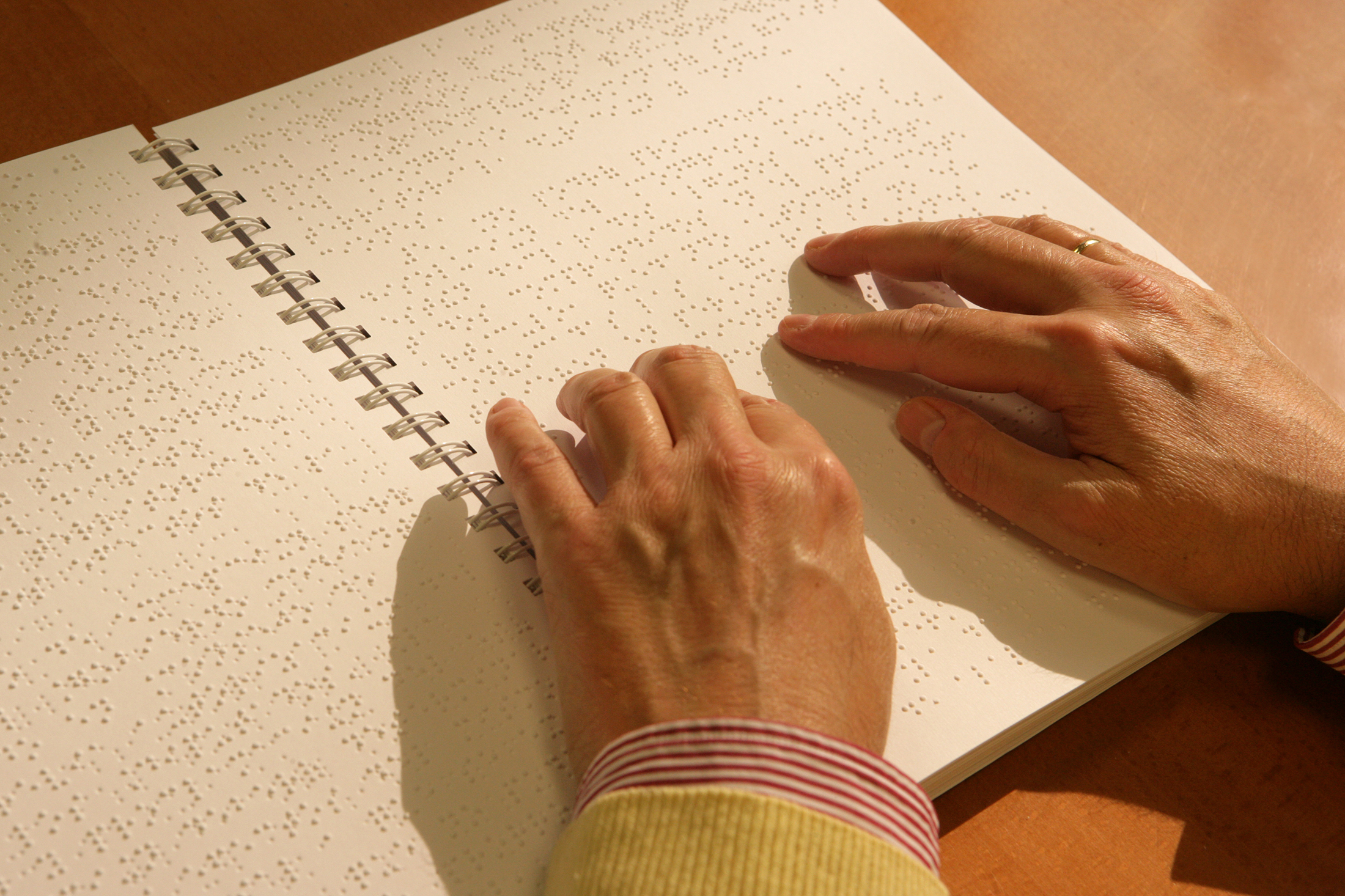 Las manos de una persona ciega leyendo un libro en braille