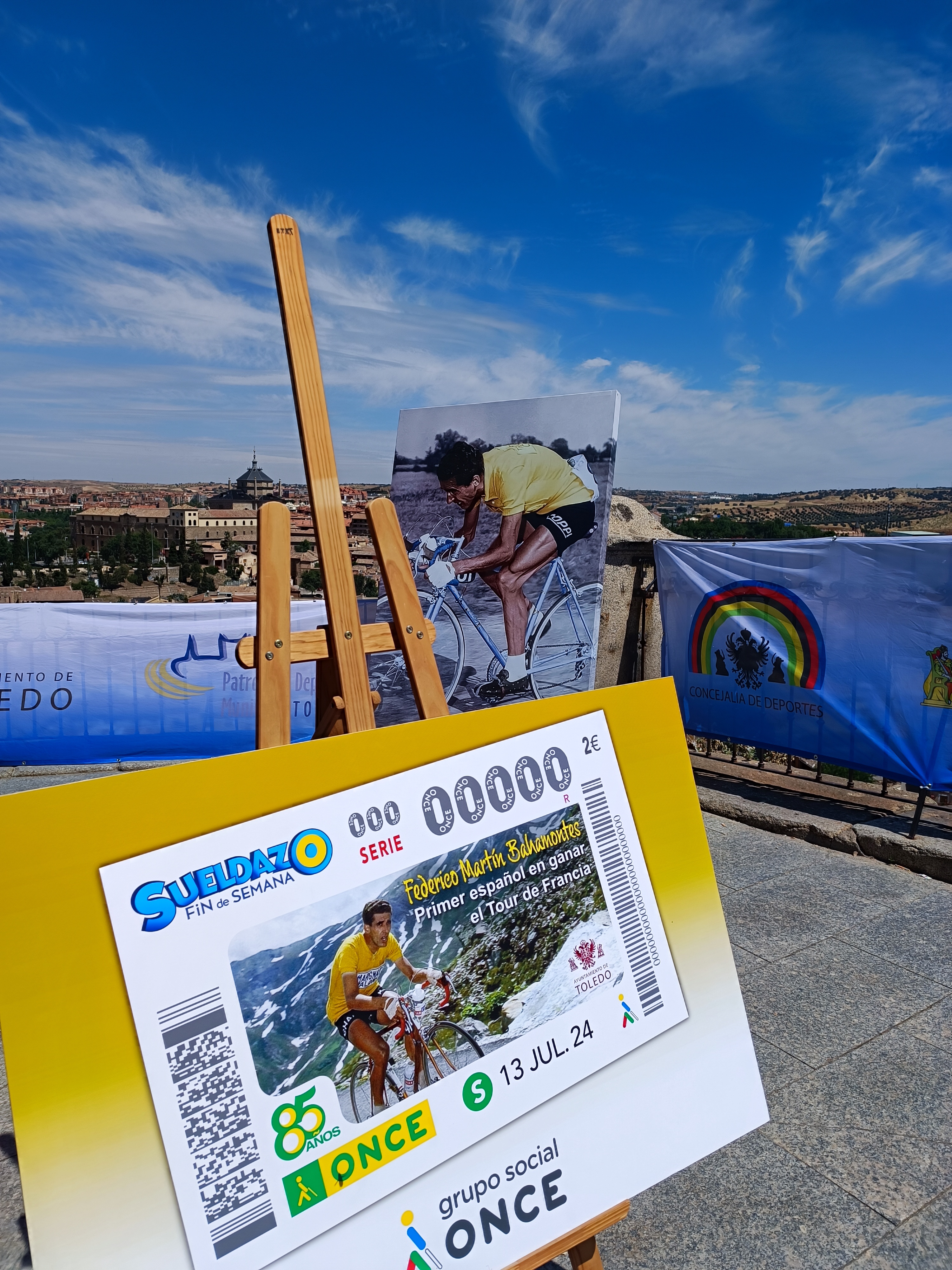 Imagen del cupón dedicado a Federico Martín Bahamontes junto a la estatua conmemorativa de la ciudad de Toledo