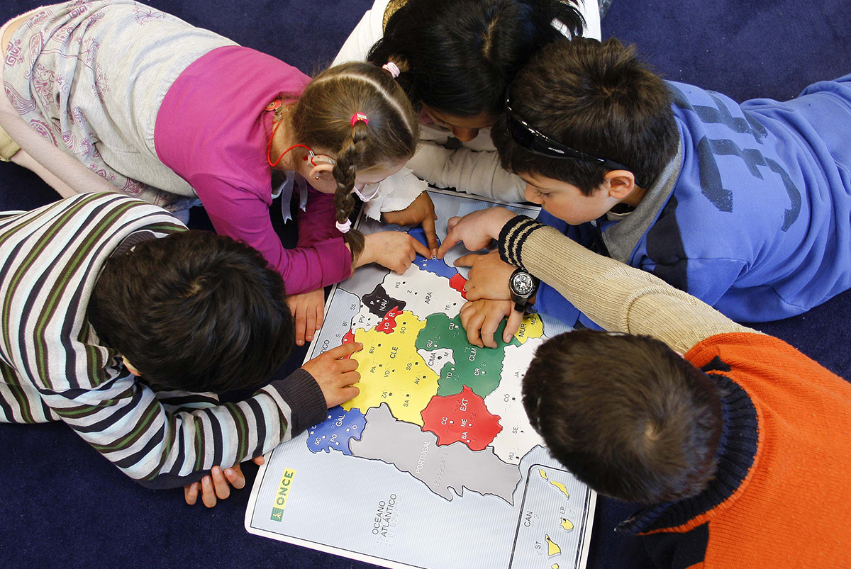 Alumnos en círculo tocando un mapa en relieve