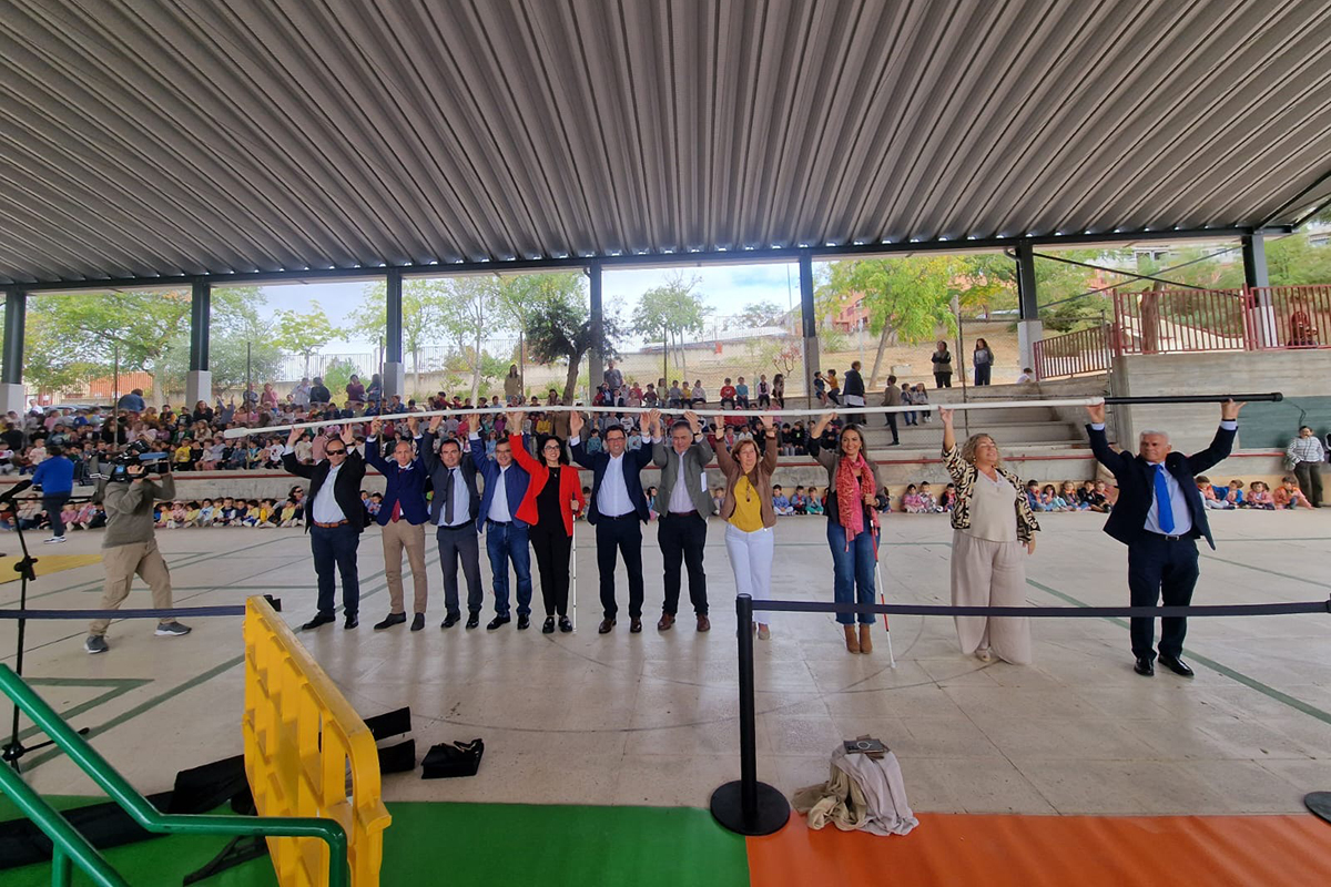 Asistentes al acto sosteniendo un bastón blanco gigante en Pista Polideportiva del CEIP Ciudad de Nara de Toledo