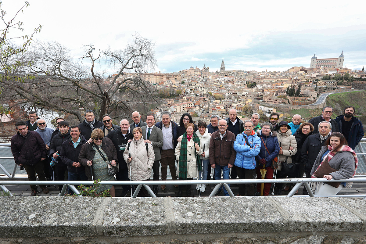 Asistentes a la presentación del cupón junto al árbol y de fondo, una panorámica de la ciudad de Toledo