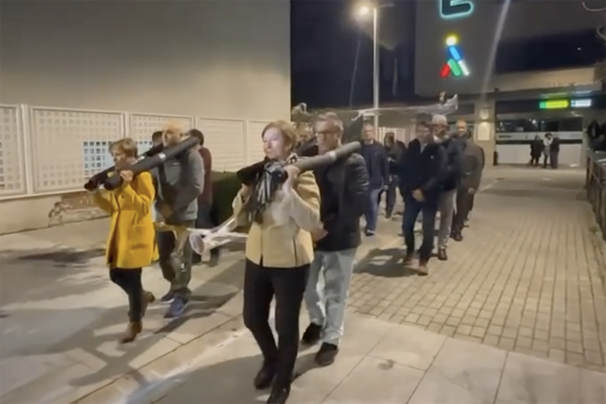 Miembros de la ONCE ensayando con los tronos de Semana Santa a las puertas de la Delegación de la ONCE de Toledo de noche. Se ve el oncelio iluminado