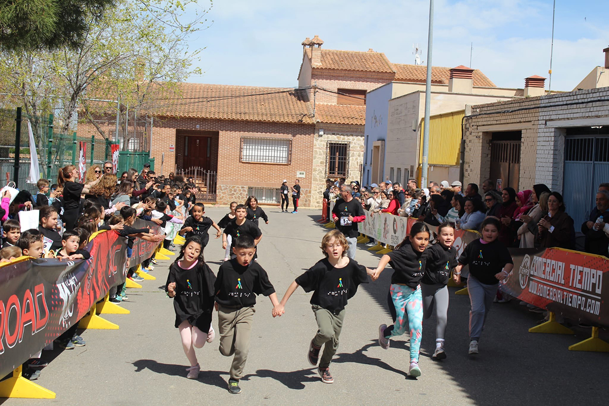 Alumnos participantes en la carrera participando cogidos de la mano mientras que son animados por compañeros y familiares