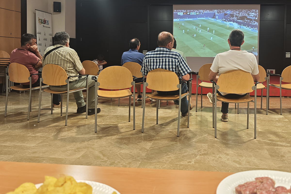 Grupo de personas viendo el partido de fútbol en una pantalla gigante del salón de actos en la Delegación Territorial de Castilla-La Mancha