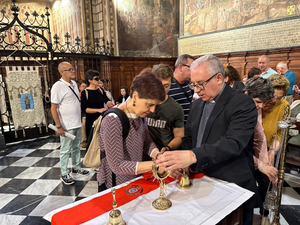 El parroco de la Catedral guiando las manos de una persona con discapacidad visual para tocar los diferentes enseres