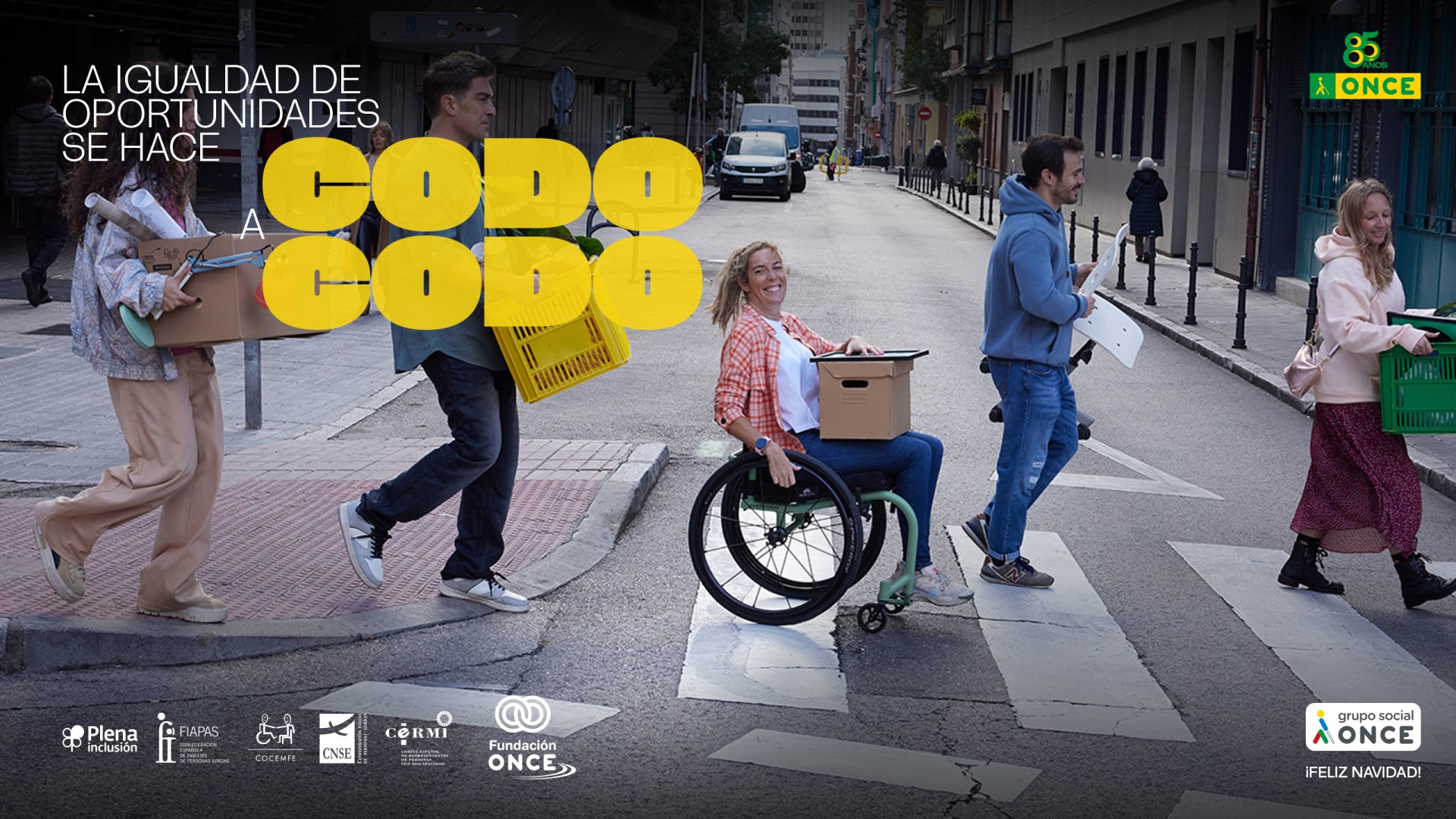 Cinco personas cruzando por un paso de peatones. Una de ellas va en silla de ruedas. La imagen tiene el texto de 