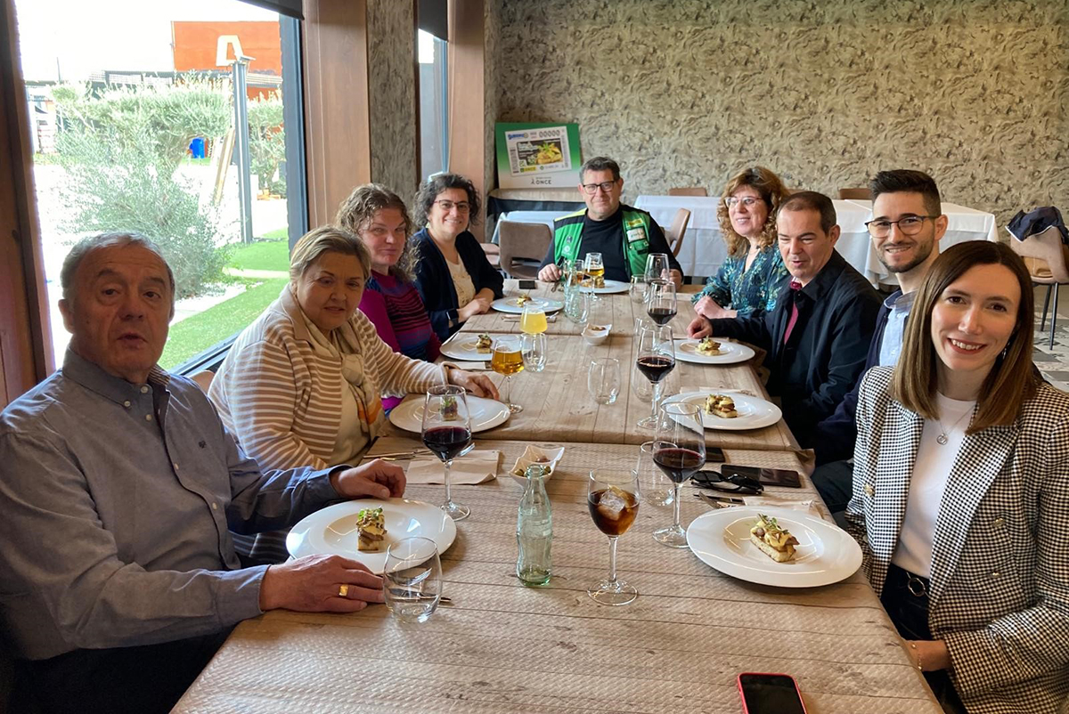 Foto de familia degustando la tapa tras la presentación de cupón con la infografía del cupón detrás