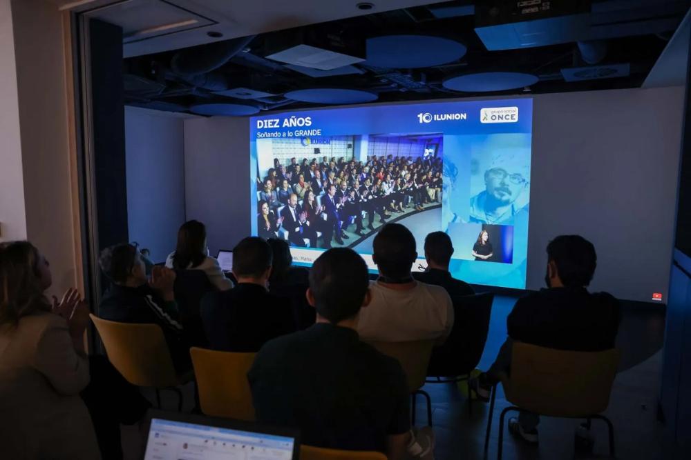 Momento del acto conmemorativo del décimo aniversario en el que se ve a los asistentes de espaldas viendo una pantalla