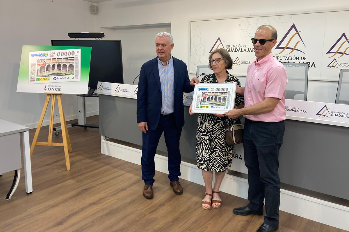 Jose Luis Vega presidente de la Diputación, Francisco Marfil director de la ONCE en Guadalajara, y Blanca del Río alcaldesa de Lupiana, sosteniendo la imagen de un cupón dedicado a Lupiana durante la presentación