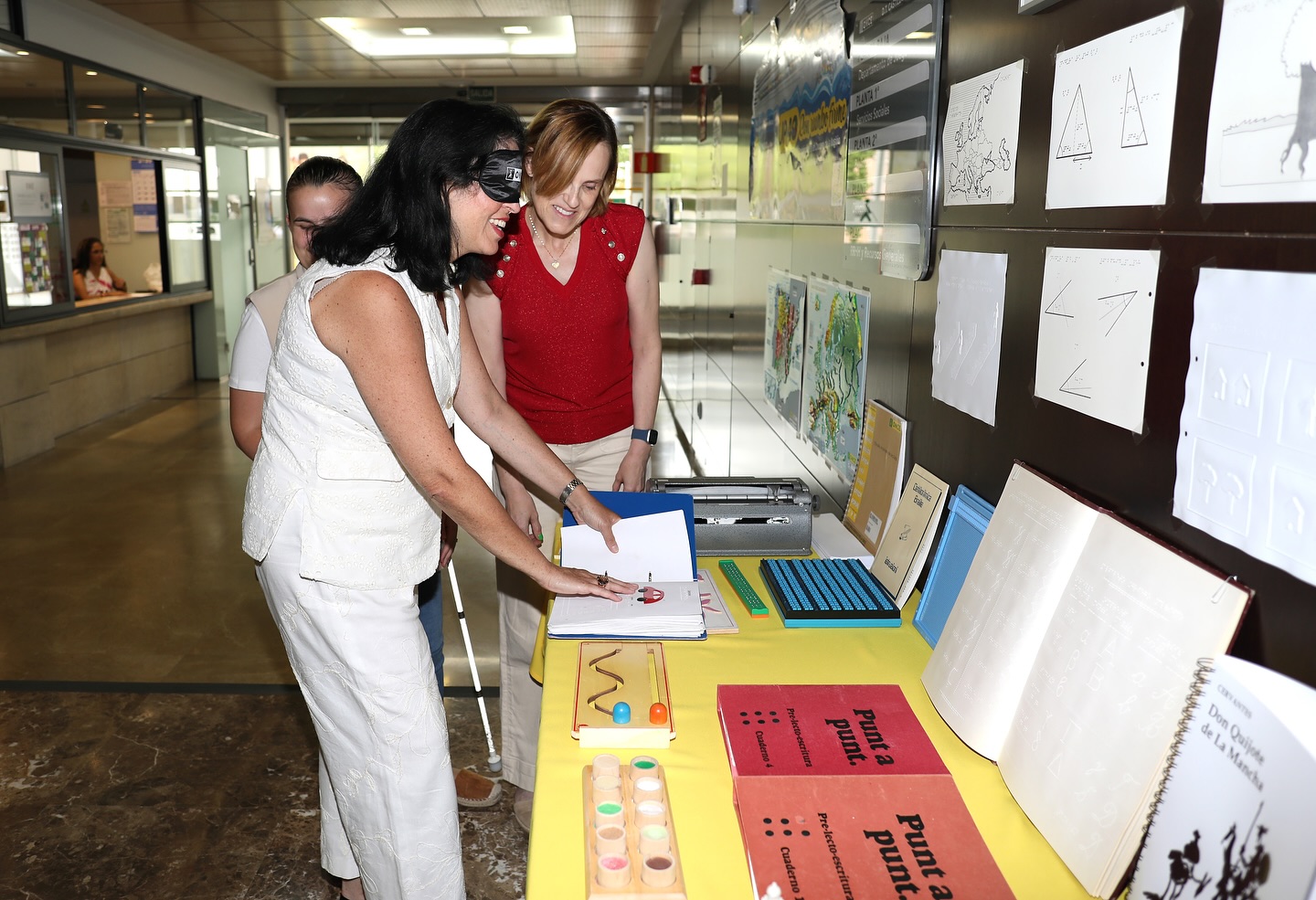 Marisol Illescas con un antifaz conociendo algunos de los materiales en braille de la ONCE