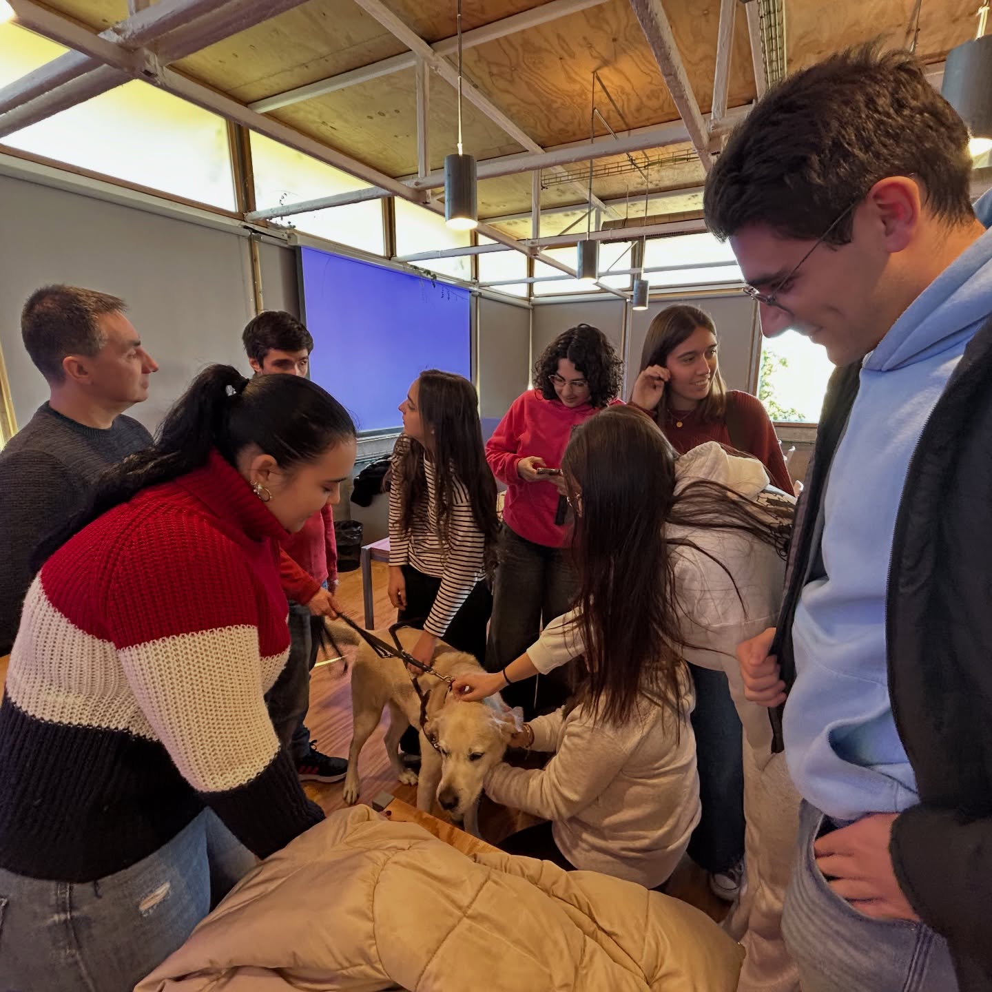 Alumnos junto a Víctor Amores y César Barquín planteando sus dudas y acariciando a Nilsen, el perro guía de Víctor