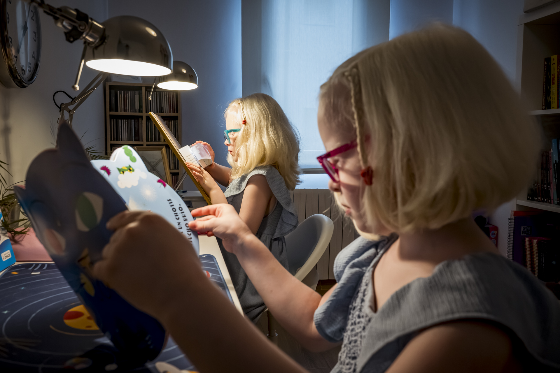 Dos niñas con discapacidad visual leyendo en su escritorio con sus adaptaciones