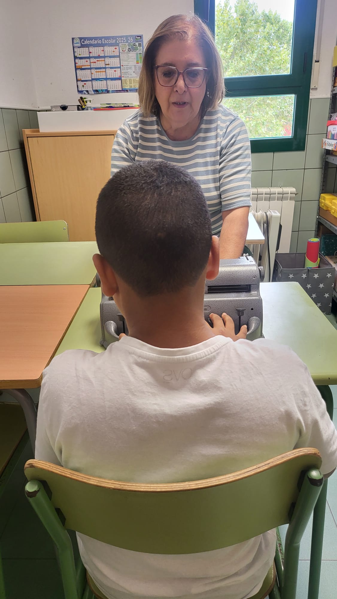 Mercedes en clase con un alumno enseñándole el uso de la máquina perkins