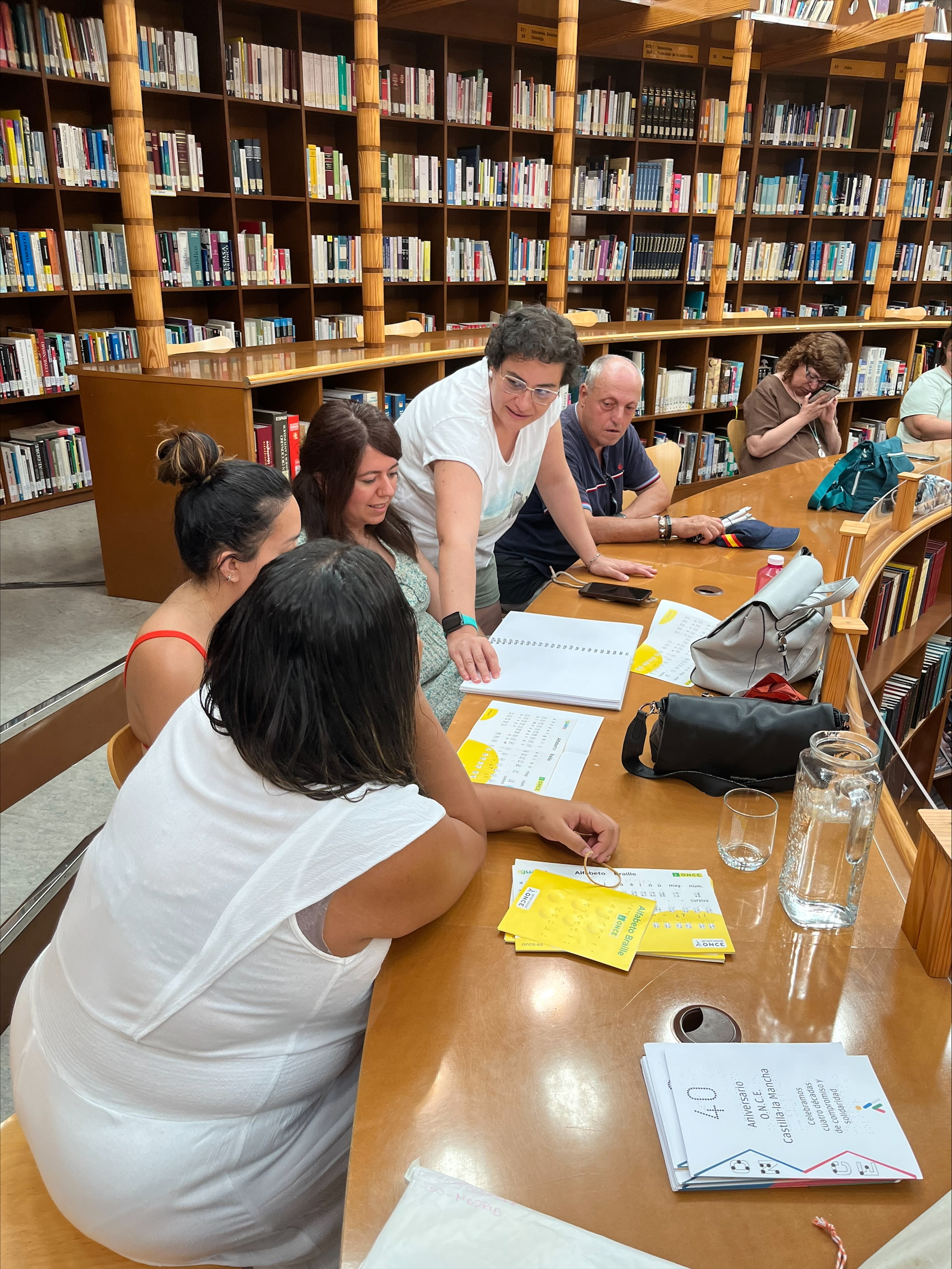 Participantes en el taller tocando textos en braille y viendo el alfabeto