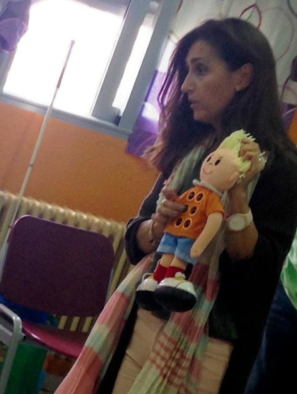 Ana María en una clase enseñando braille con el muñeco braillín