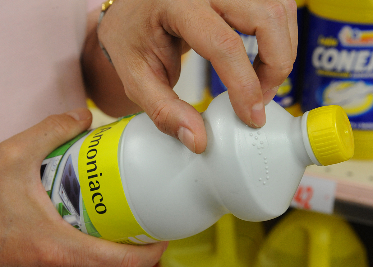 Unas manos tocando el etiquetado braille de una botella de amoniaco