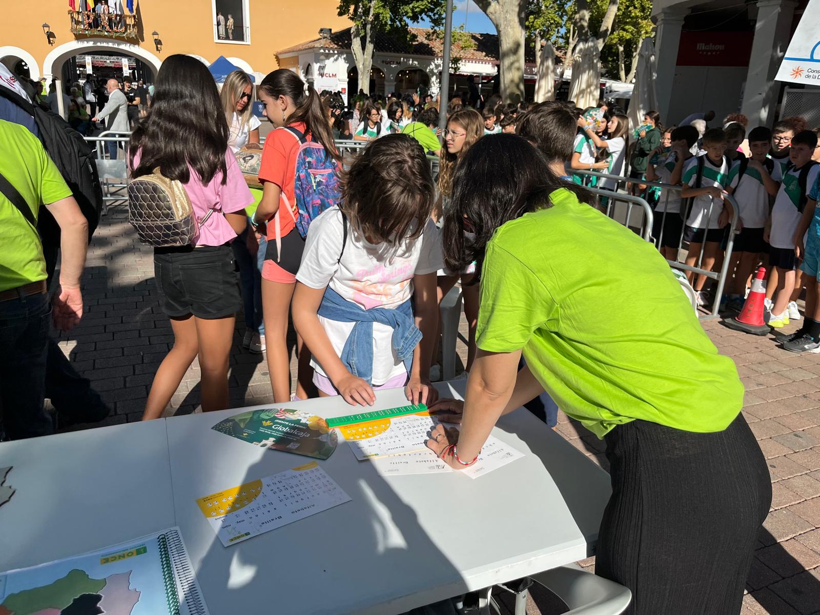 Una profesora de la ONCE enseñando braille a una visitante del stand de la ONCE en el Día de la Discapacidad en la Feria de Albacete