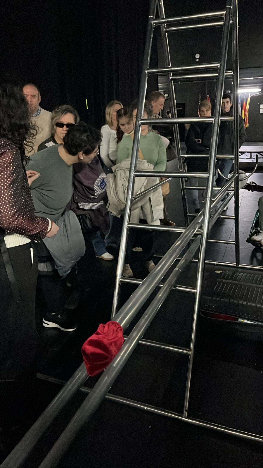 Asistentes entre bambalinas tocando la escalara, elemento de uno de los espectáculos, mientras la audiodescribe Belén